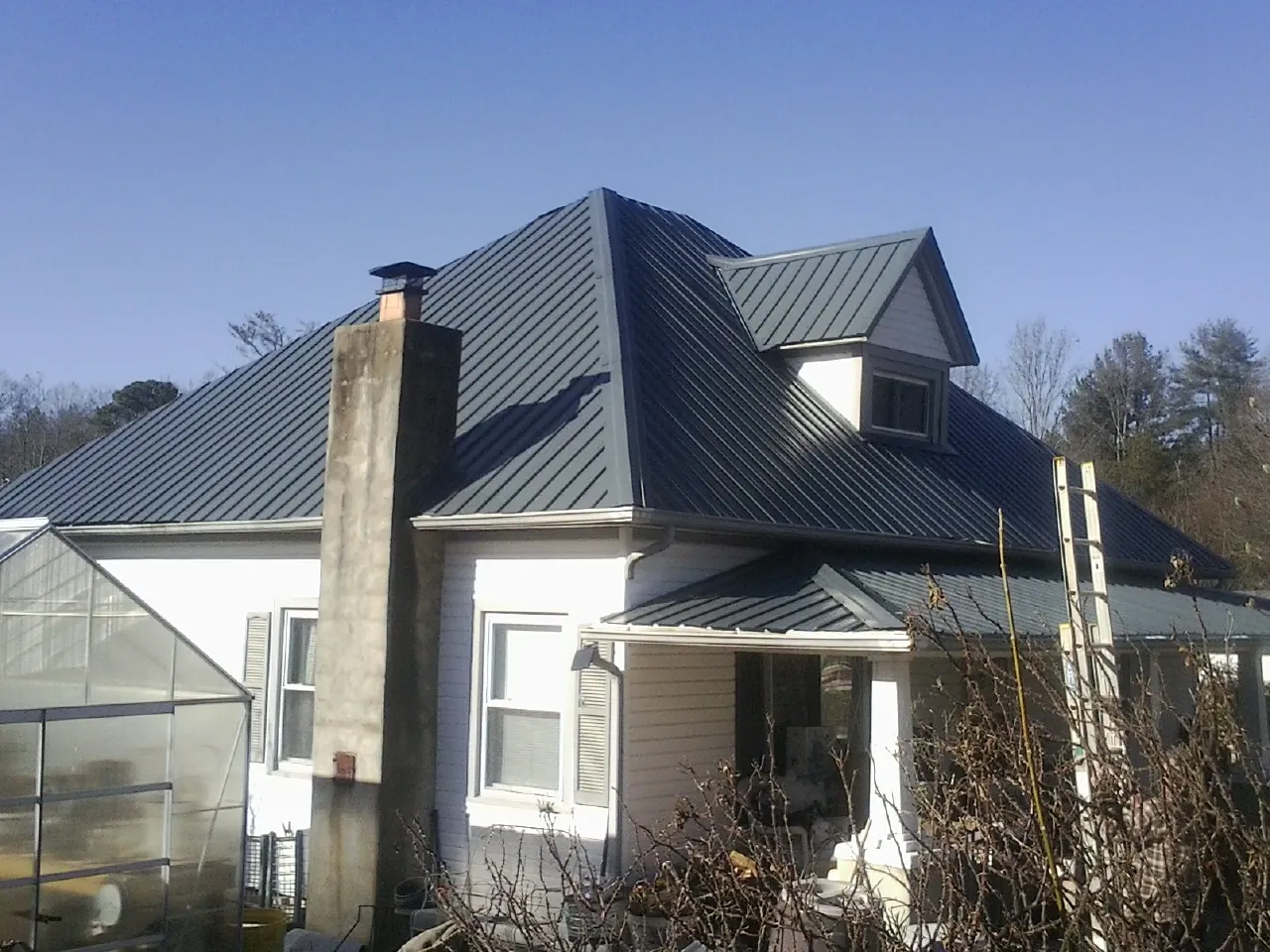 Dark blue standing seam metal roof on a white farmhouse with dormer — Slate & Tile Roof Repair by Roofing Brothers in Steilacoom