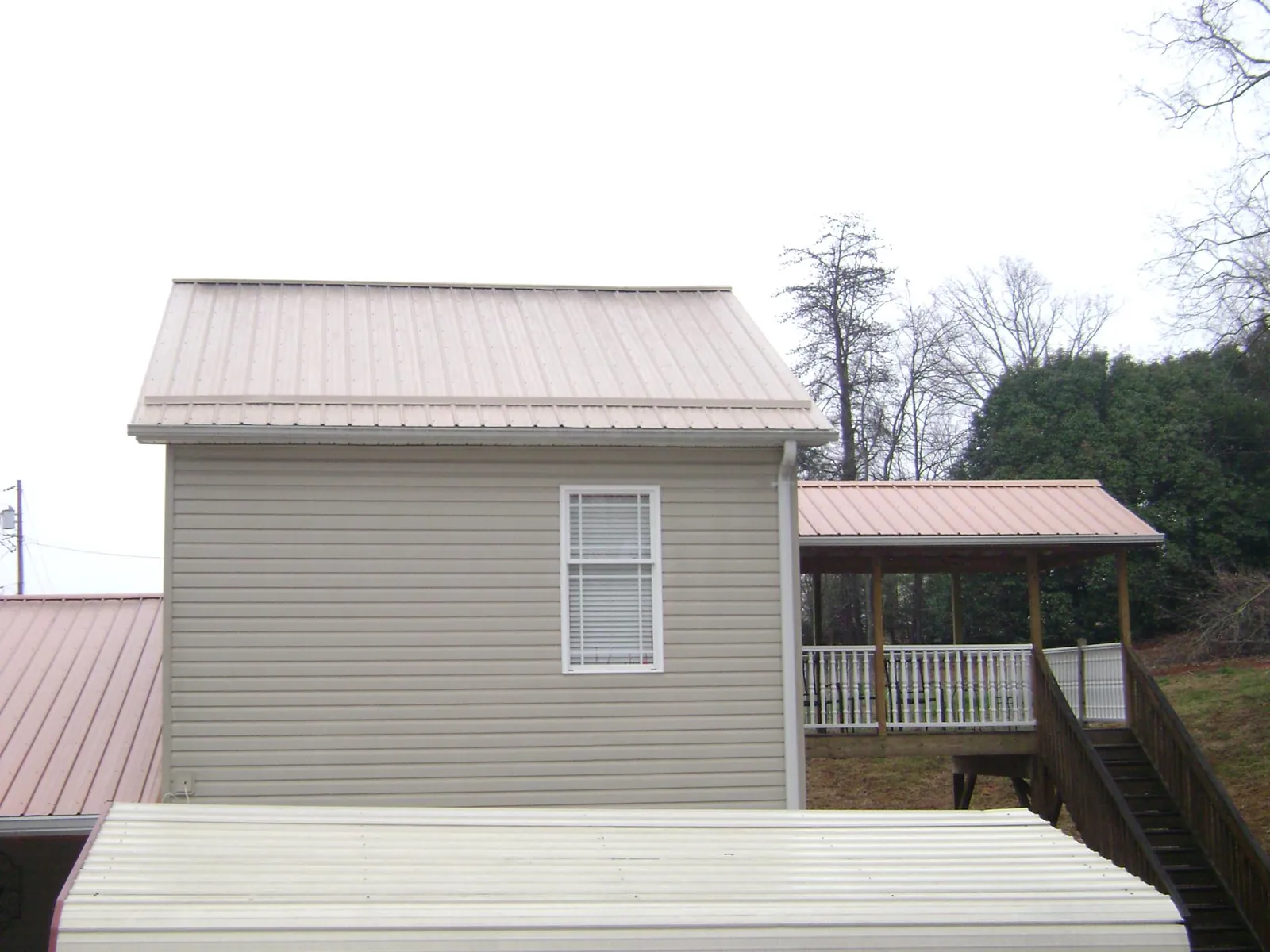 Tan metal roofs on a two story addition and attached porch, from a Roof Replacement job in Steilacoom