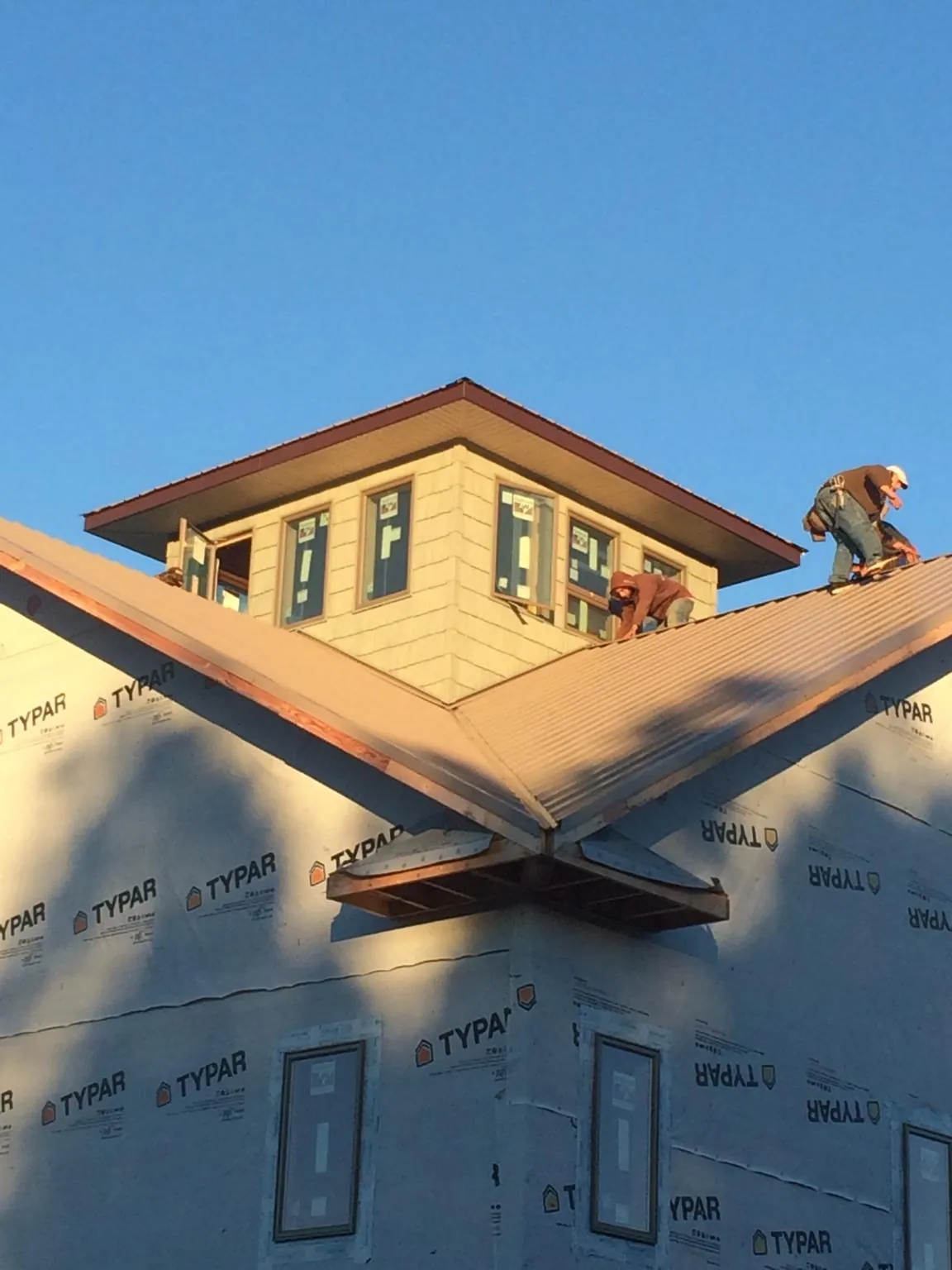 Roofers working around a rooftop cupola on a new metal roof at sunset — Roof Waterproofing in Steilacoom by Roofing Brothers